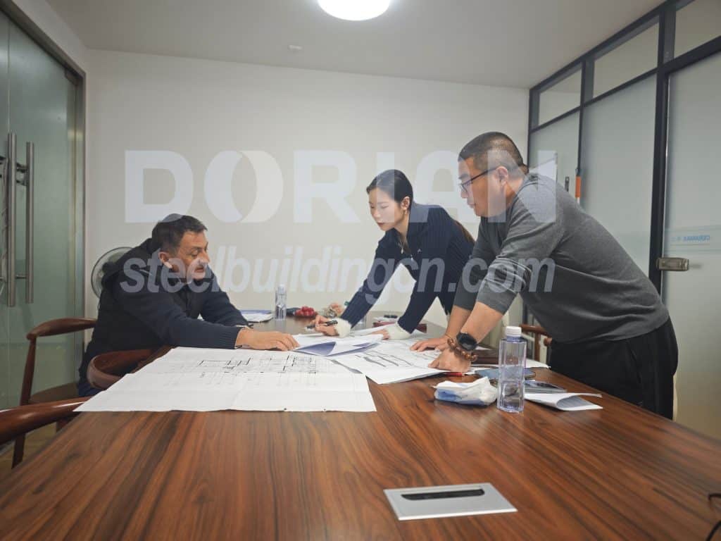 Business meeting discussing steel building project plans in an office setting.