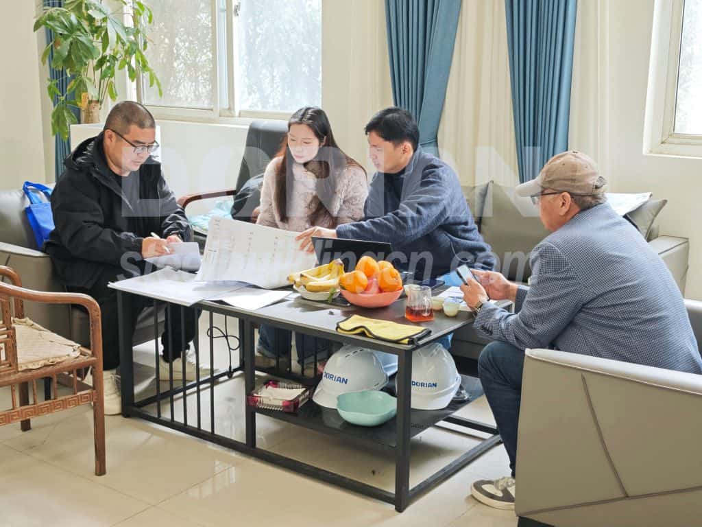 Business meeting with engineers and clients discussing steel building project plans indoors.