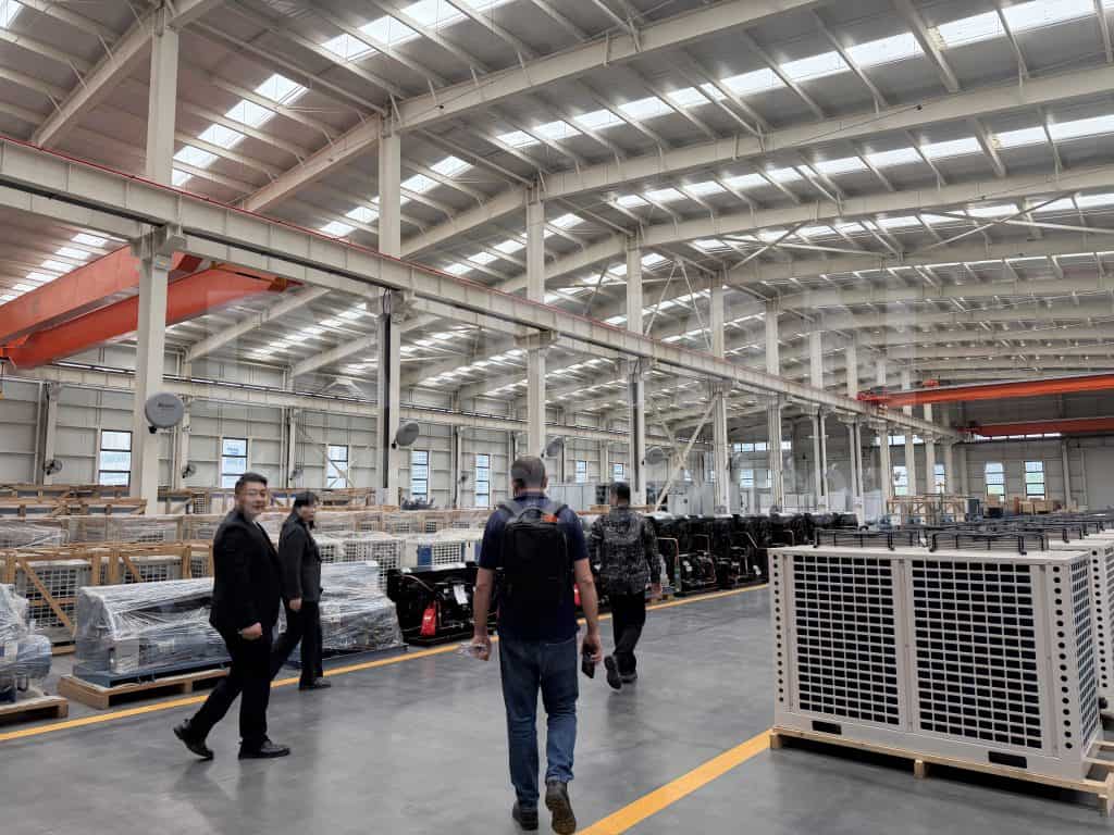 High-ceiling steel building with workers inspecting equipment inside a factory.