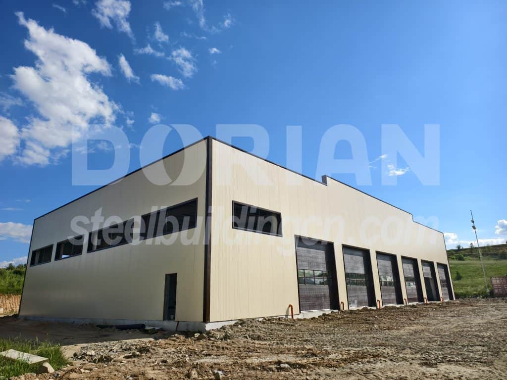 Large steel structure with multiple garage doors and windows under a blue sky.