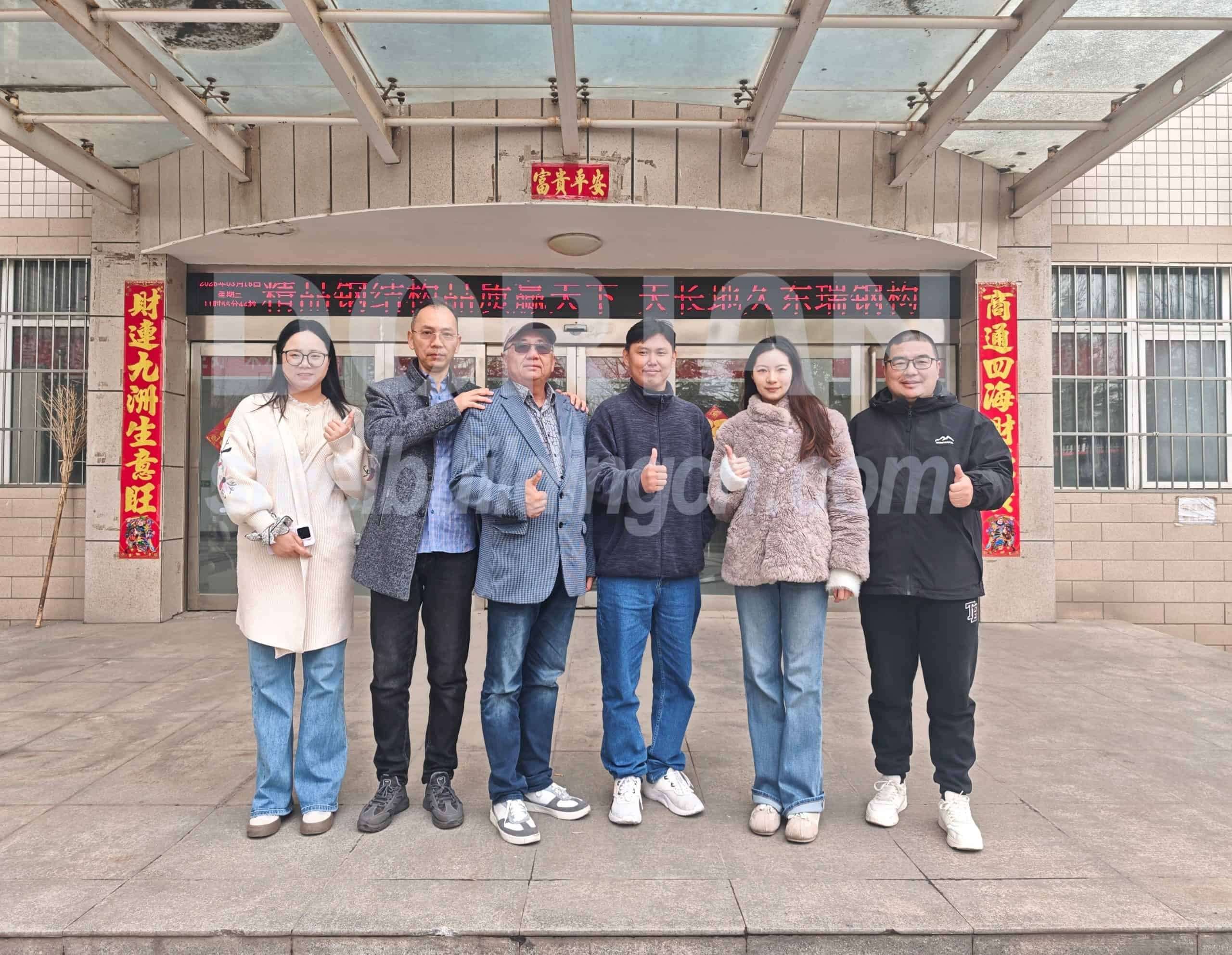 A diverse group of six people posing confidently outside a steel building facility. Welcome American client’s architects to visit Dorian factory and discuss the project details 4